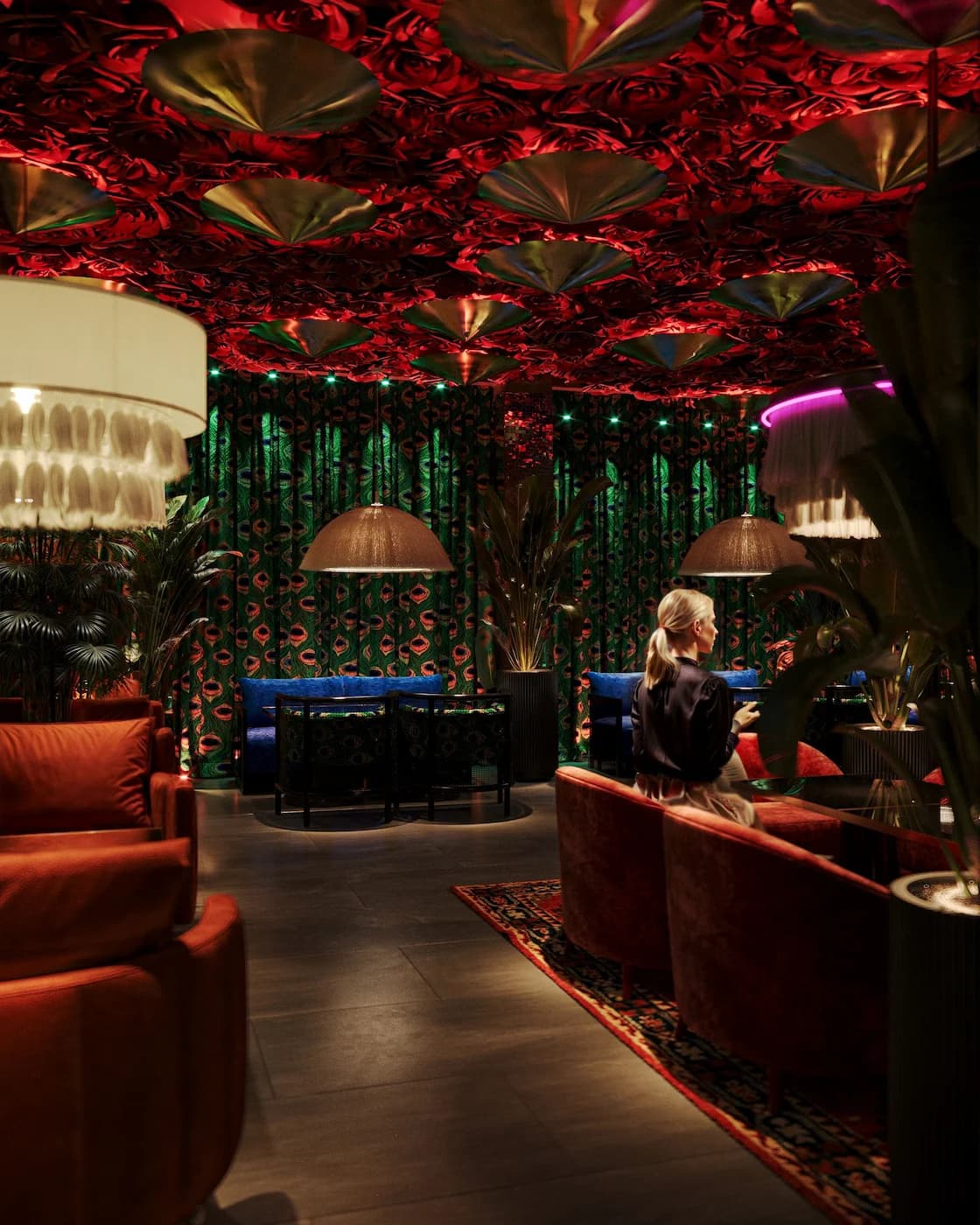 Atmospheric restaurant lounge with floral ceiling decor, green pendant lights and colourful seating