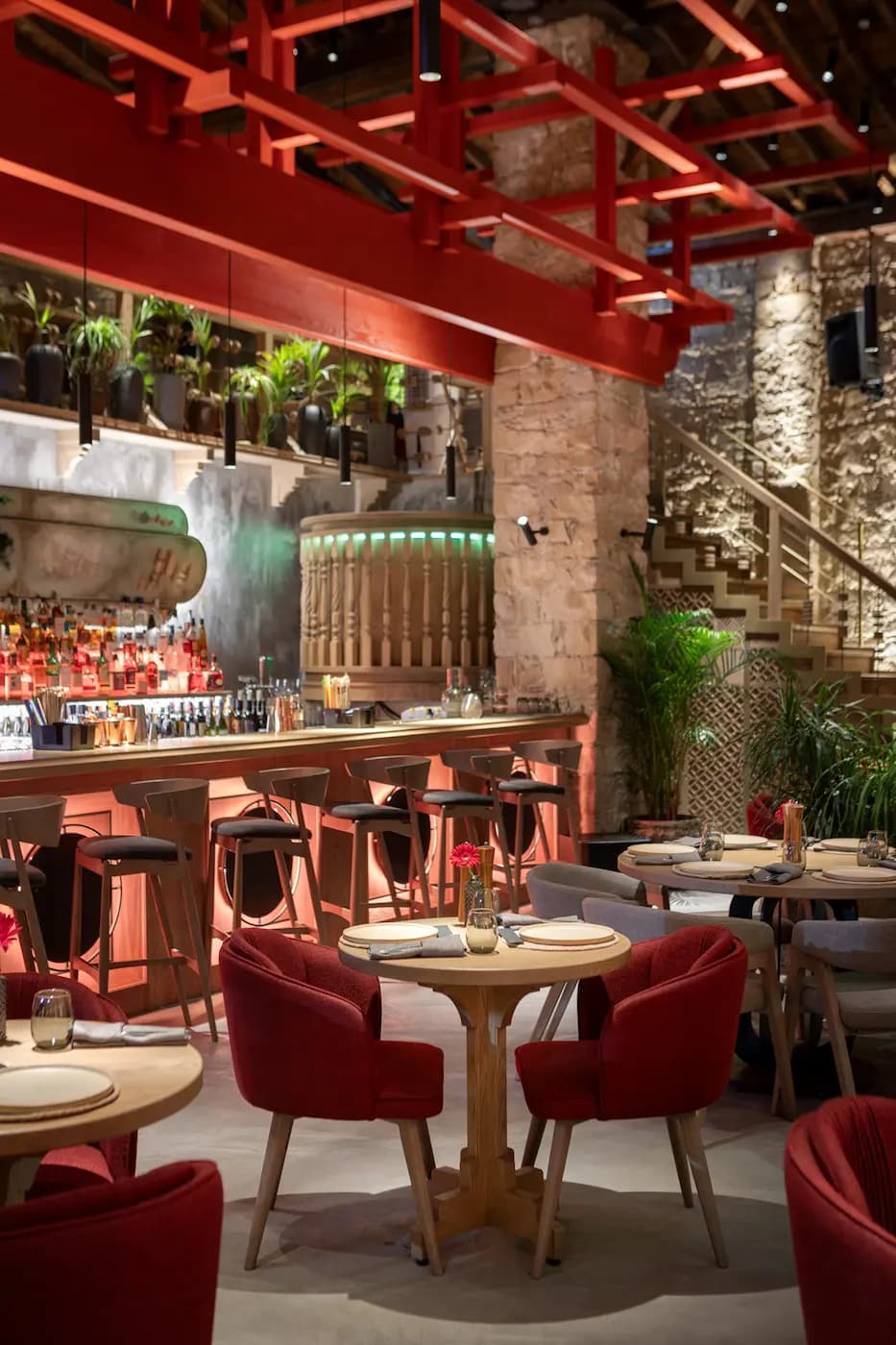 Lila Izakaya dining area with burgundy seating, greenery and warm lighting
