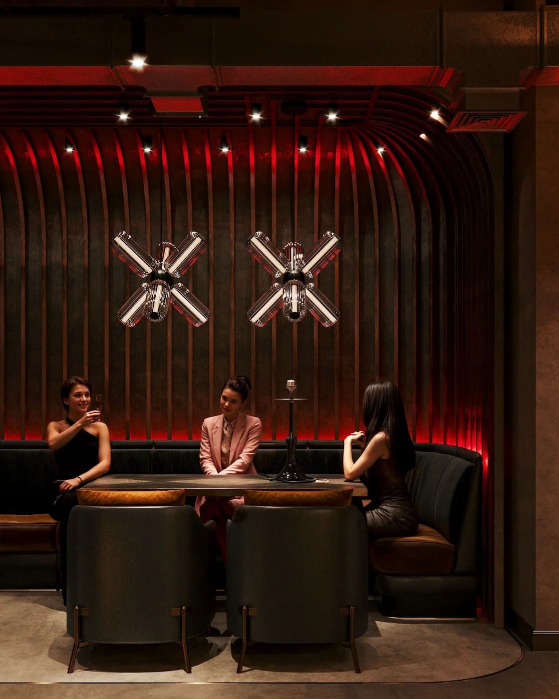 Private booth with crossed symbolic wall elements and deep red illumination