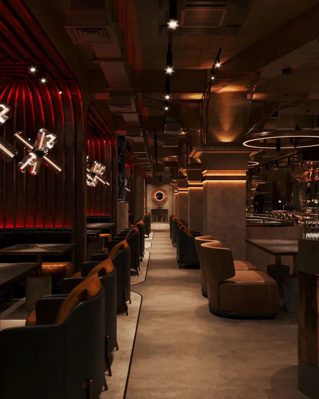Layered seating area with dark timber, bronze surfaces and red accent lighting