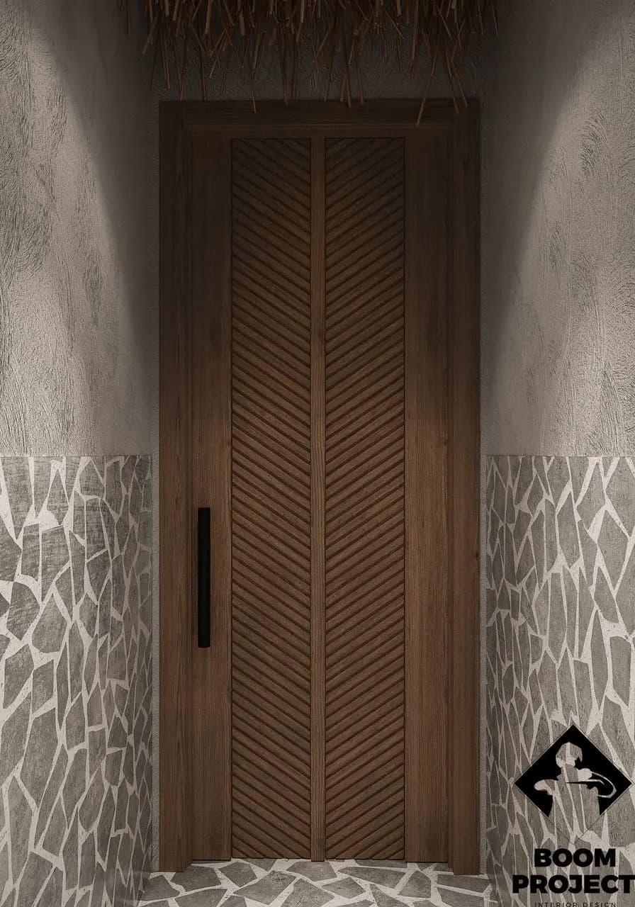 Decorative timber restroom door beside a softly patterned plaster wall