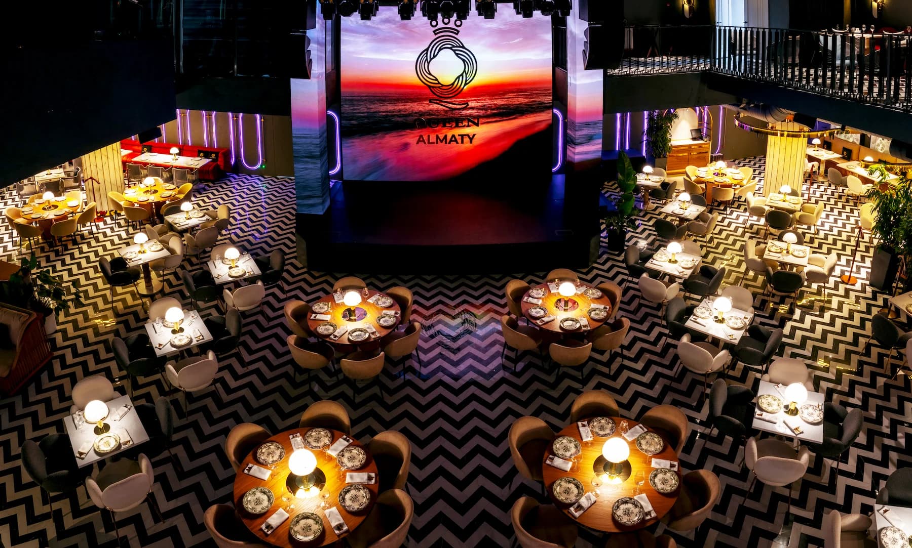 Queen performance hall with illuminated stage and circular dining tables