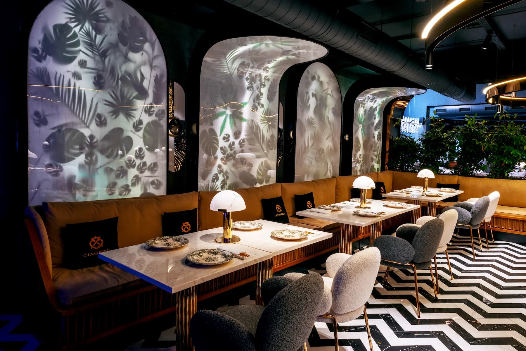 Intimate restaurant zone with marble tables, timber partitions and botanical artwork
