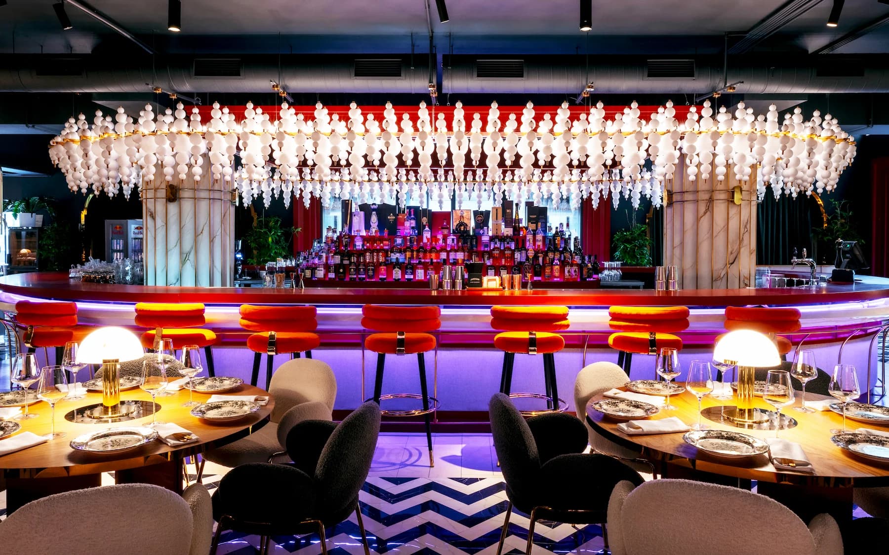 Performance space with red lighting, bottle installation and graphic patterned flooring