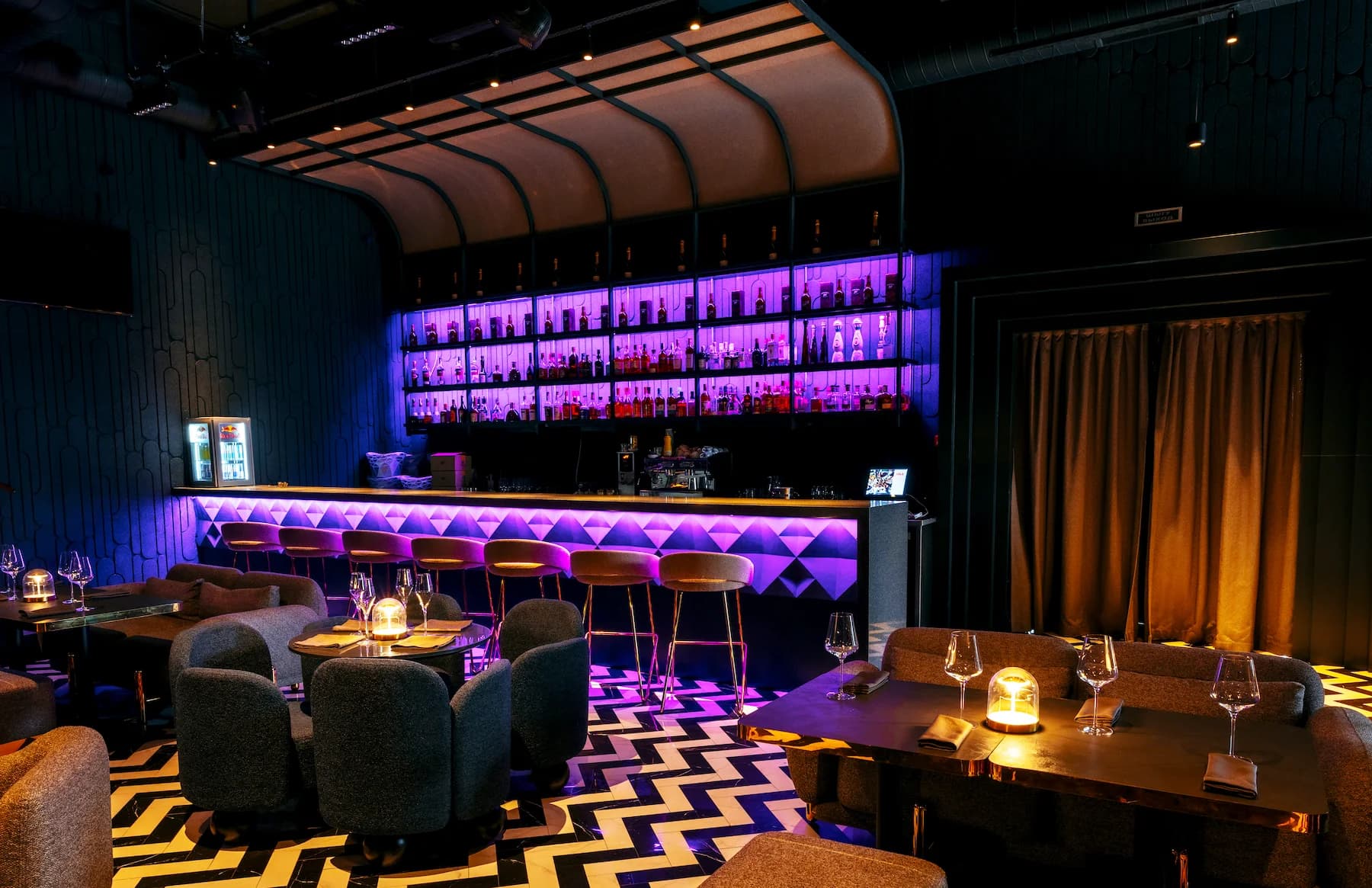Entrance to the Queen bar framed by red curtains and graphic black-and-white flooring