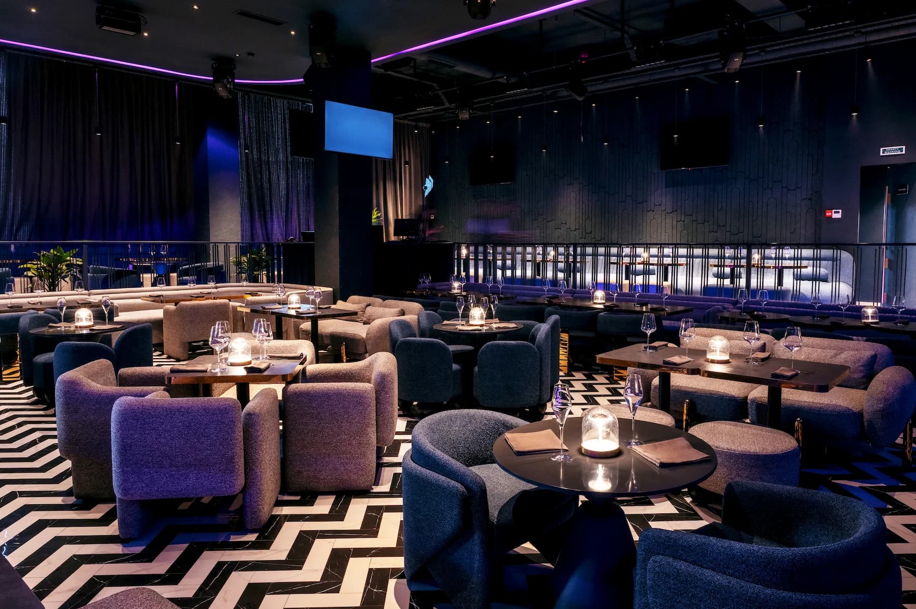 Restaurant lounge with sculptural lighting, patterned floor and curved upholstered seating