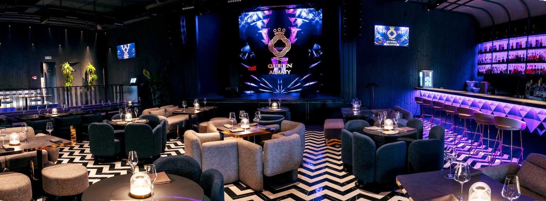 Queen karaoke bar with illuminated bottle shelves and violet architectural lighting