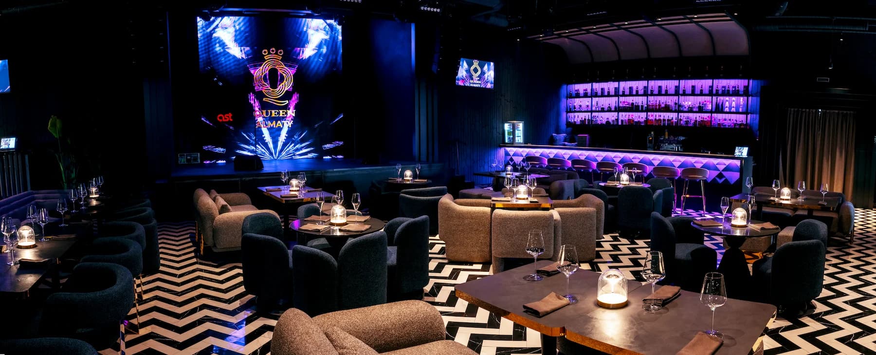 Karaoke lounge with dark curtains, patterned flooring and intimate table groups
