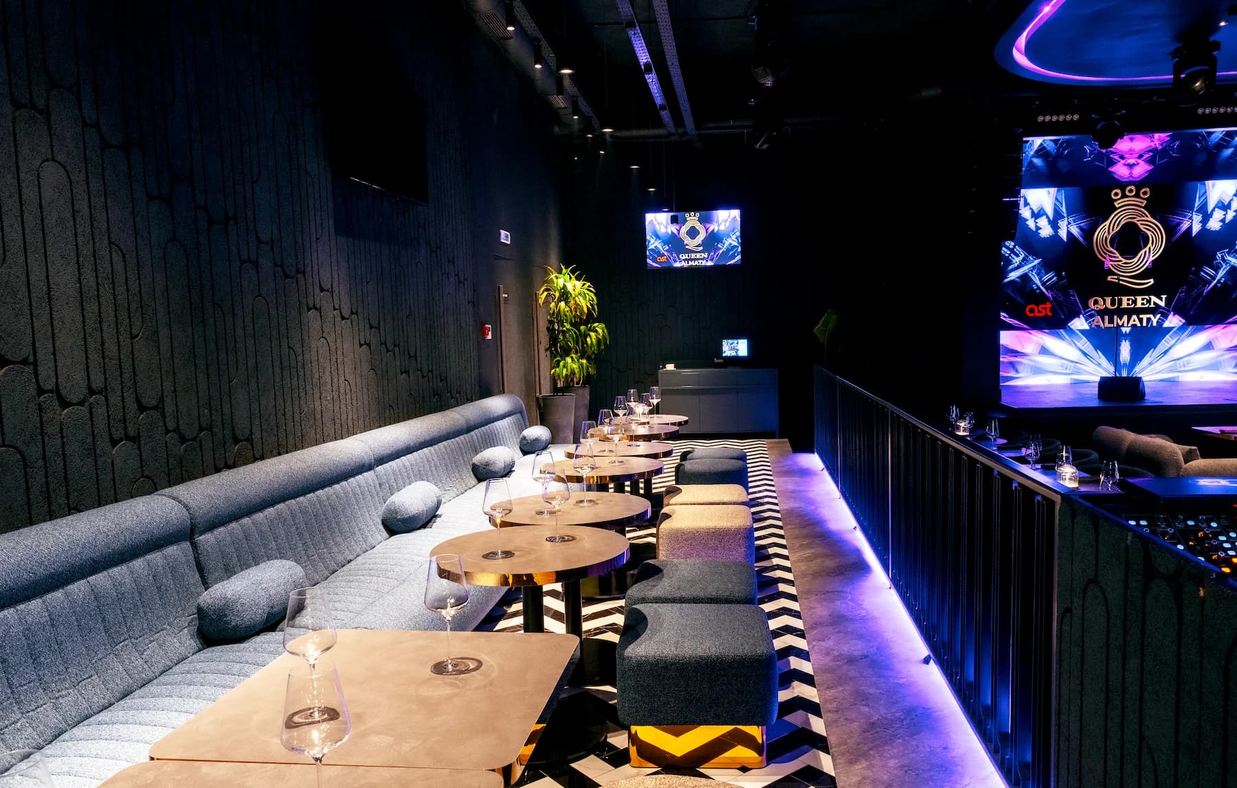 Nightclub-style lounge with violet bar lighting and panoramic multimedia display