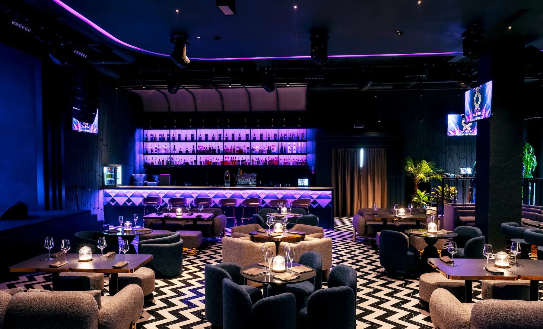 Dark karaoke room with intimate sofas, pendant lights and graphic patterned floor