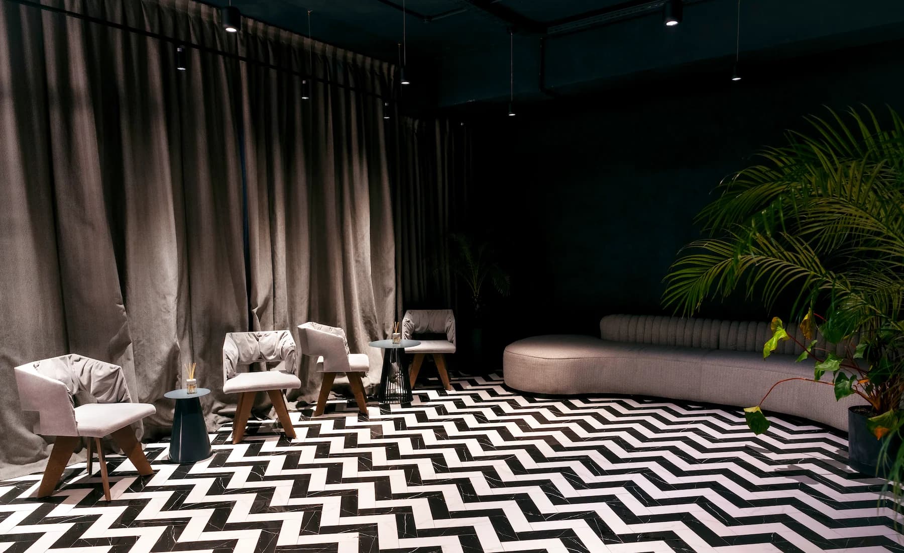 Private dining lounge with long table, sculptural pendant lights and dark curtains