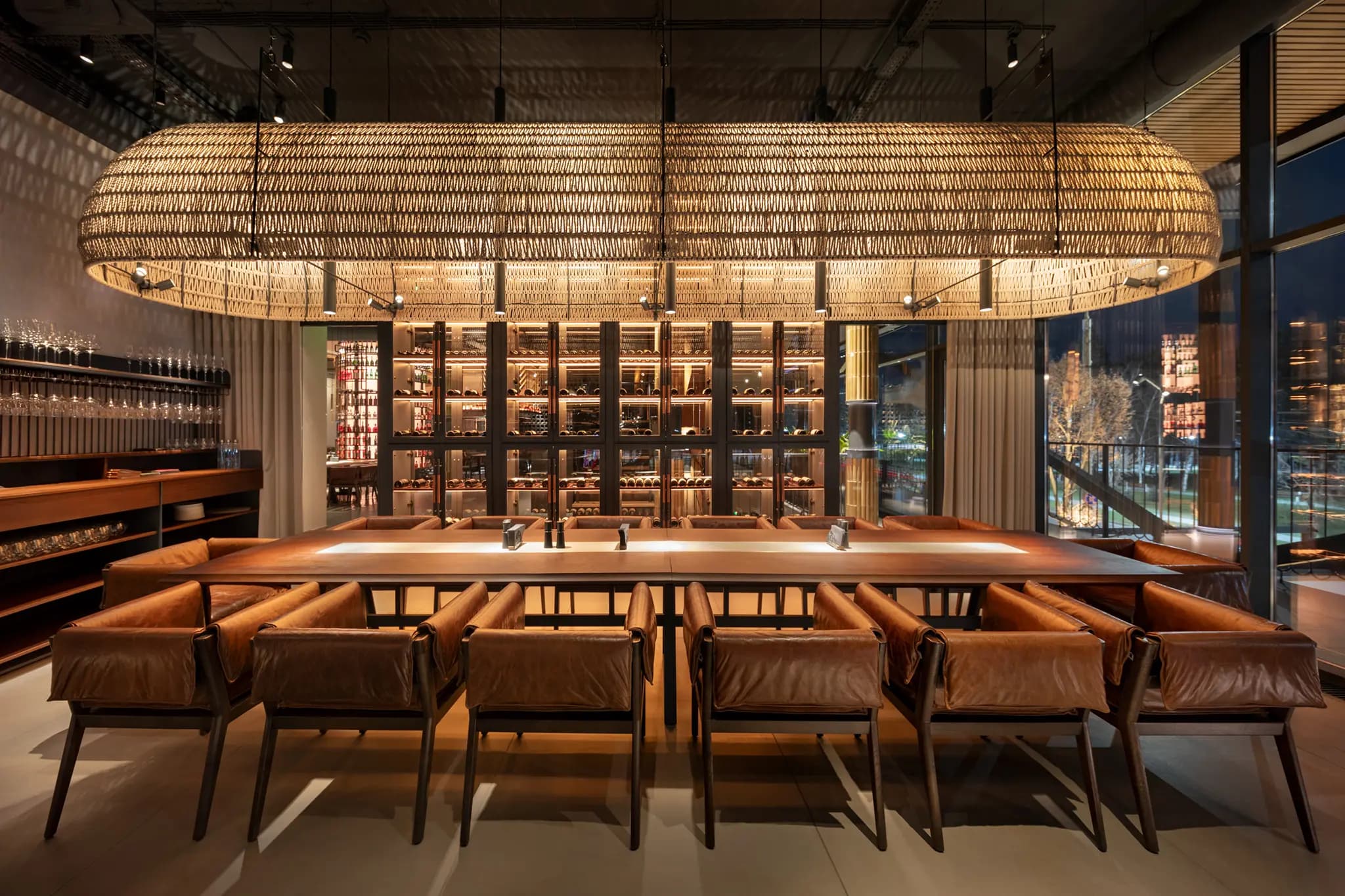 Modern restaurant interior at SOL in Chișinău featuring custom lighting, timber architecture and a sculptural wine display designed by BOOM Project.