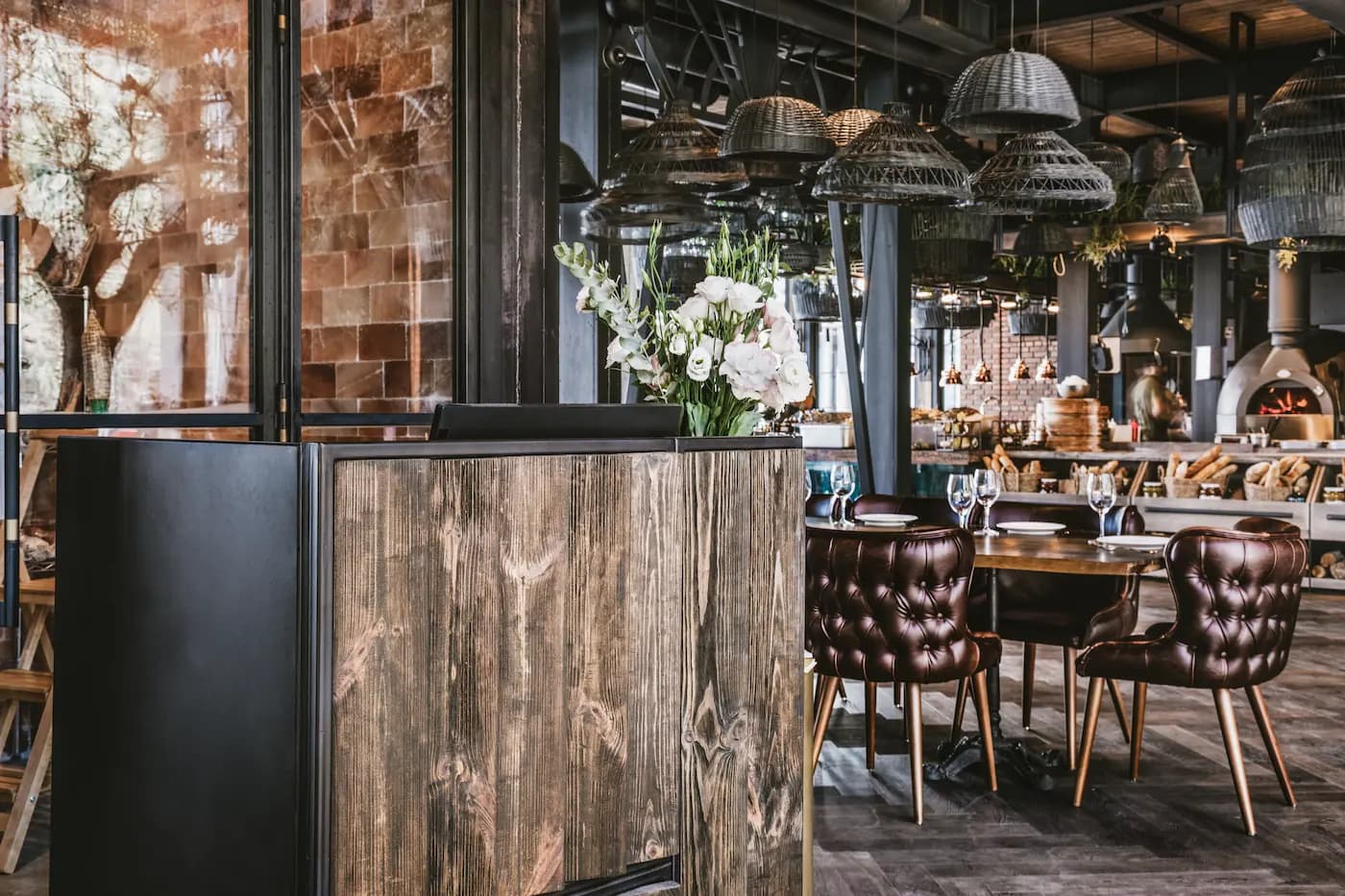 Rustic timber host stand beside an aged brick column and the open restaurant interior.