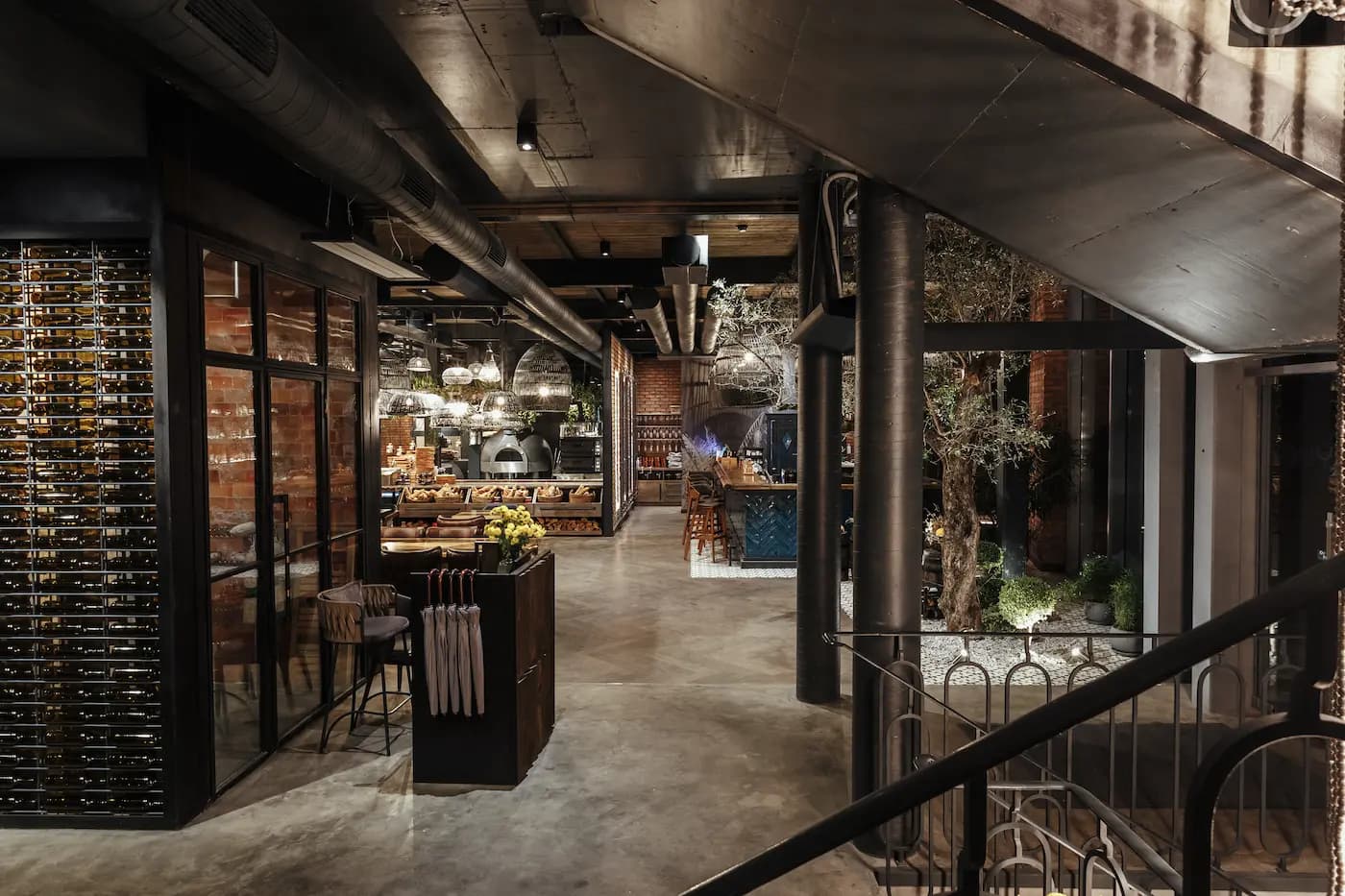 Entrance passage with aged brickwork, a timber reception counter, dark metal and indoor planting.