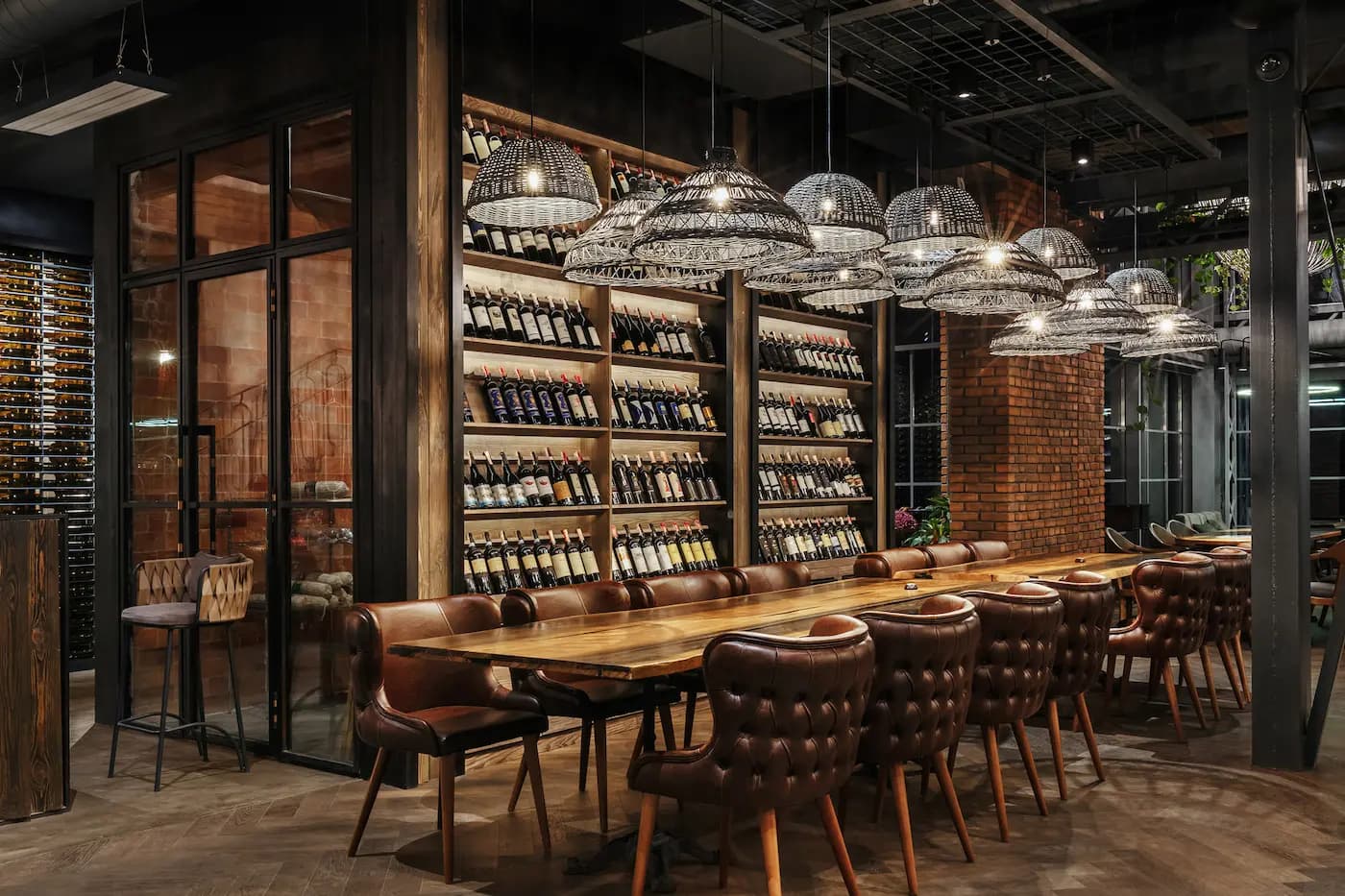 Intimate leather seating area framed by brick columns and floor-to-ceiling illuminated wine shelving.