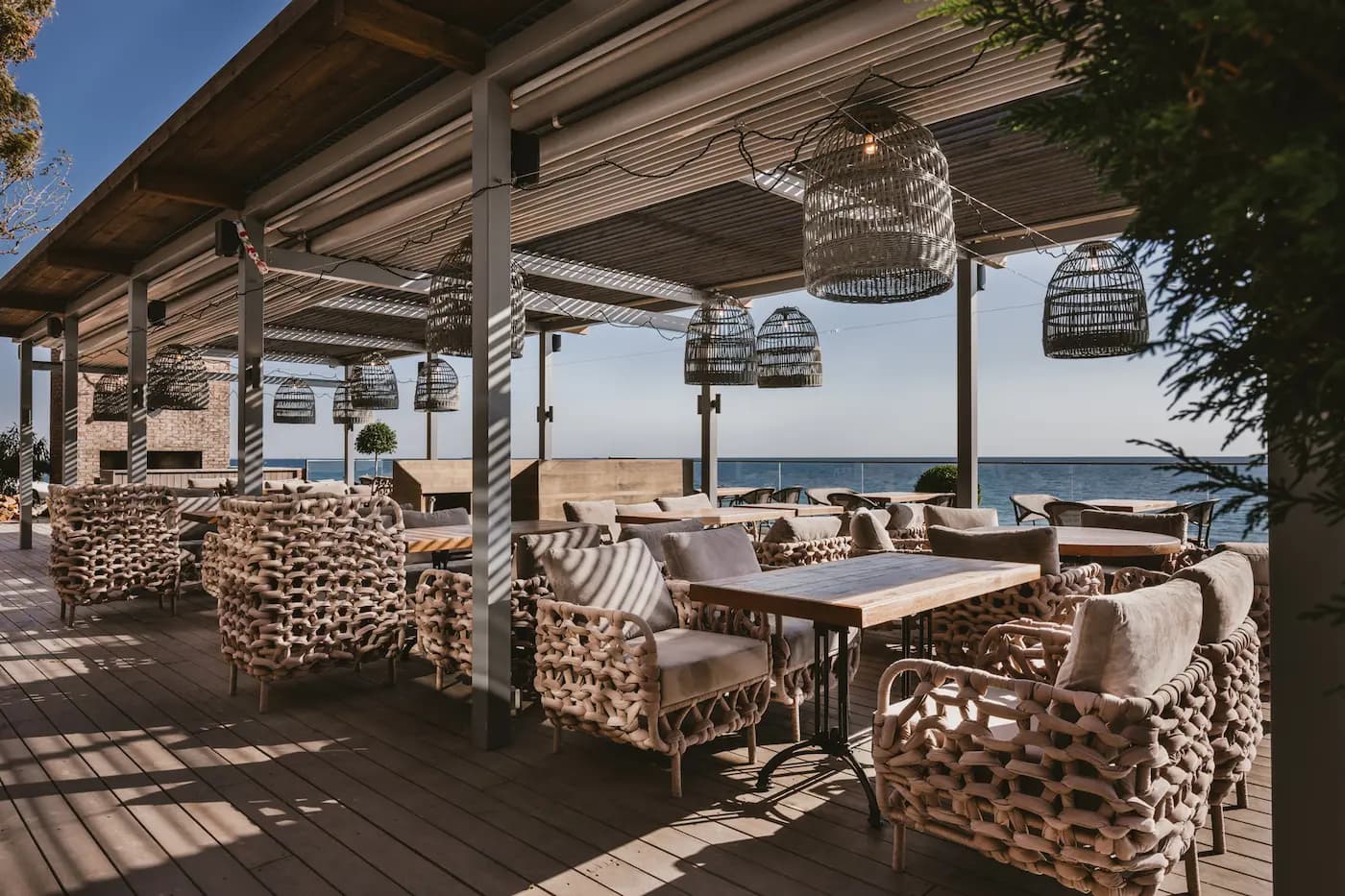 Sea-facing terrace with woven ceiling panels, patterned seating and views across the Black Sea.