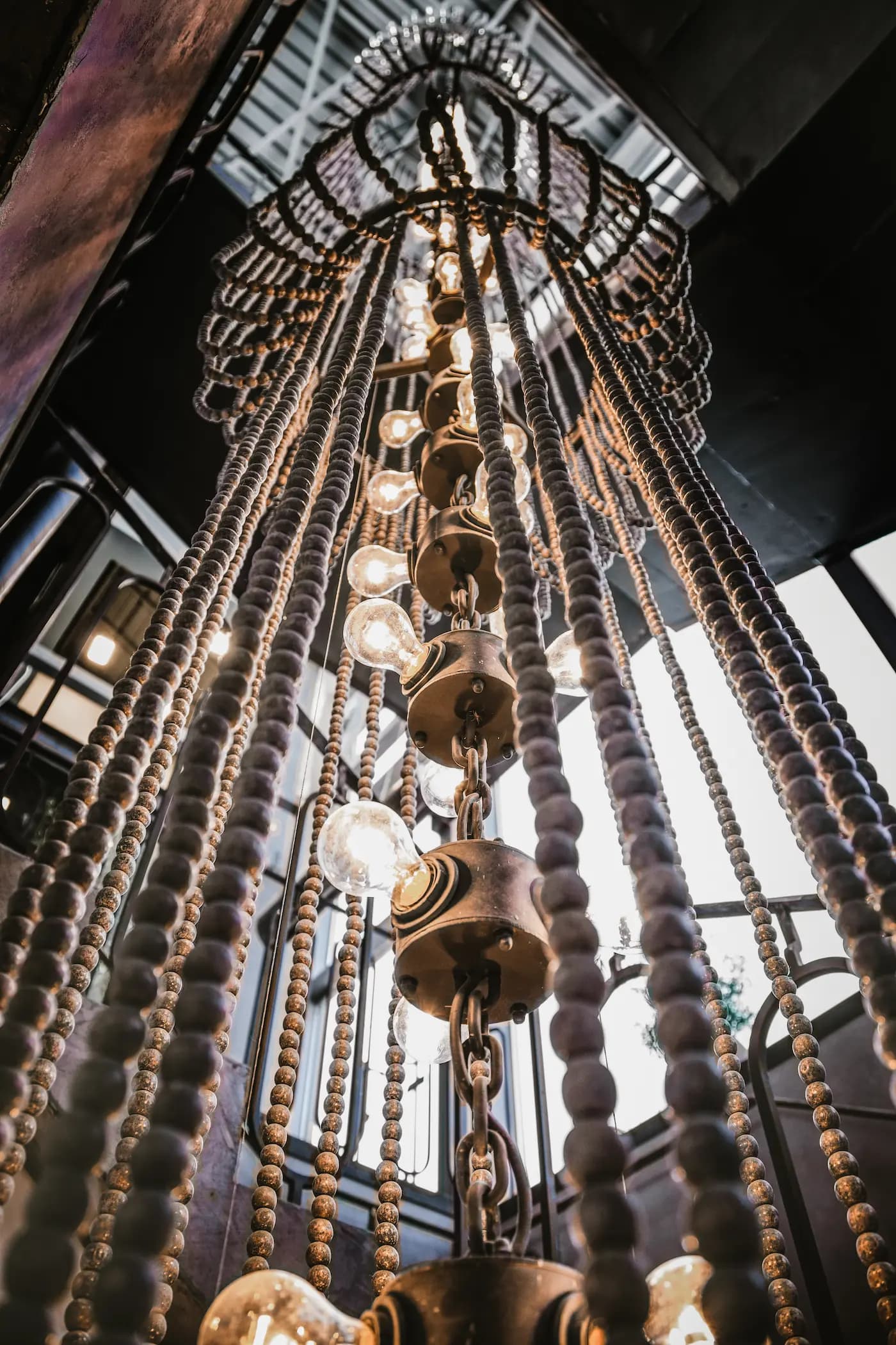 Upward view of a large custom chandelier composed of timber beads and glowing light sources.