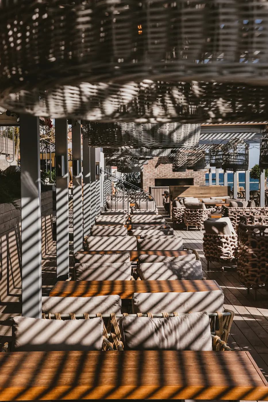 Main dining hall of YUG Restaurant with patterned seating, tall windows and suspended planting.