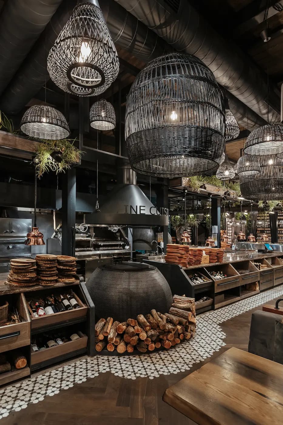 Open kitchen bar with a sculptural metal canopy, natural planting and a long service counter.