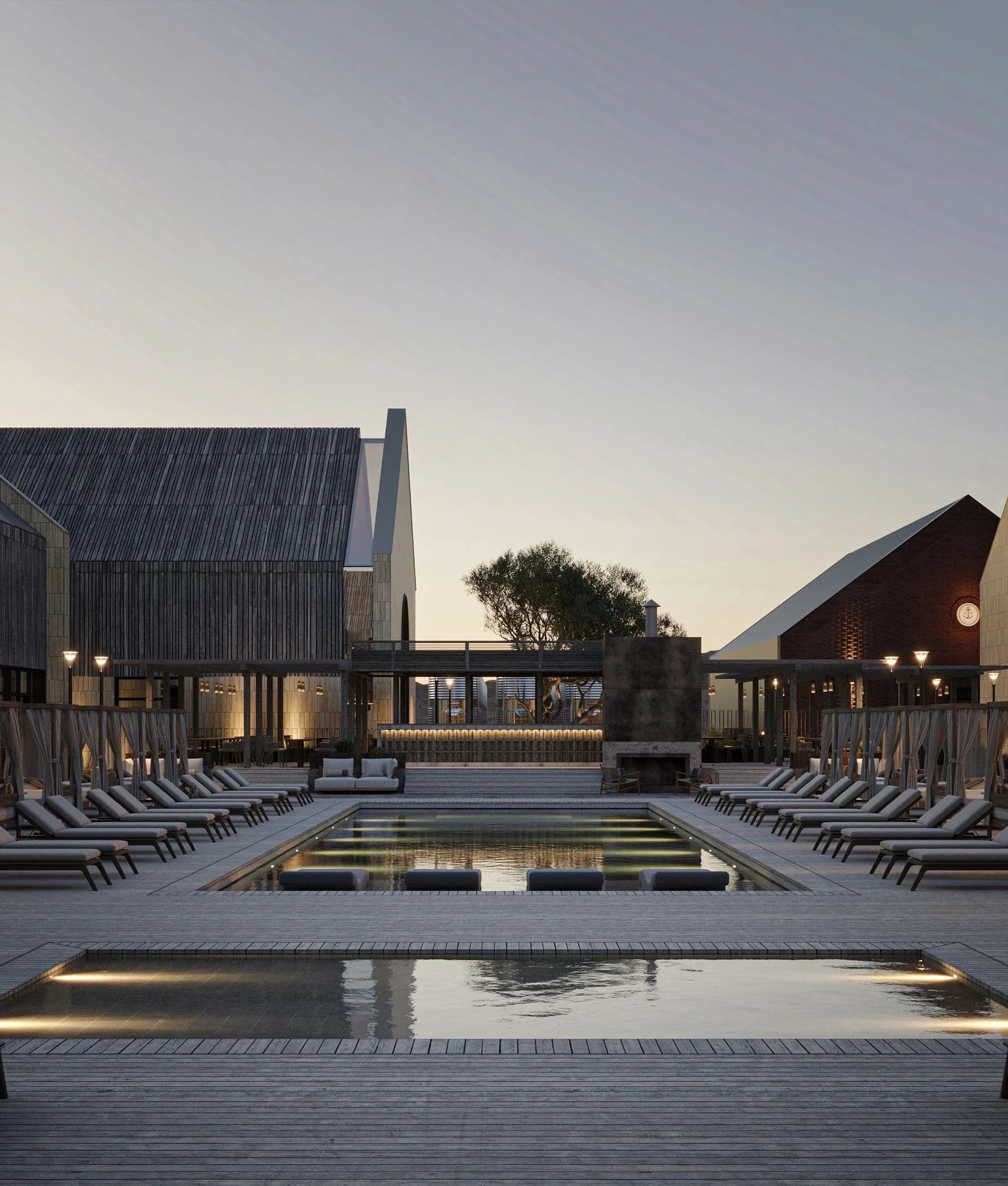 Pool at dusk with sun loungers against gable-roofed buildings