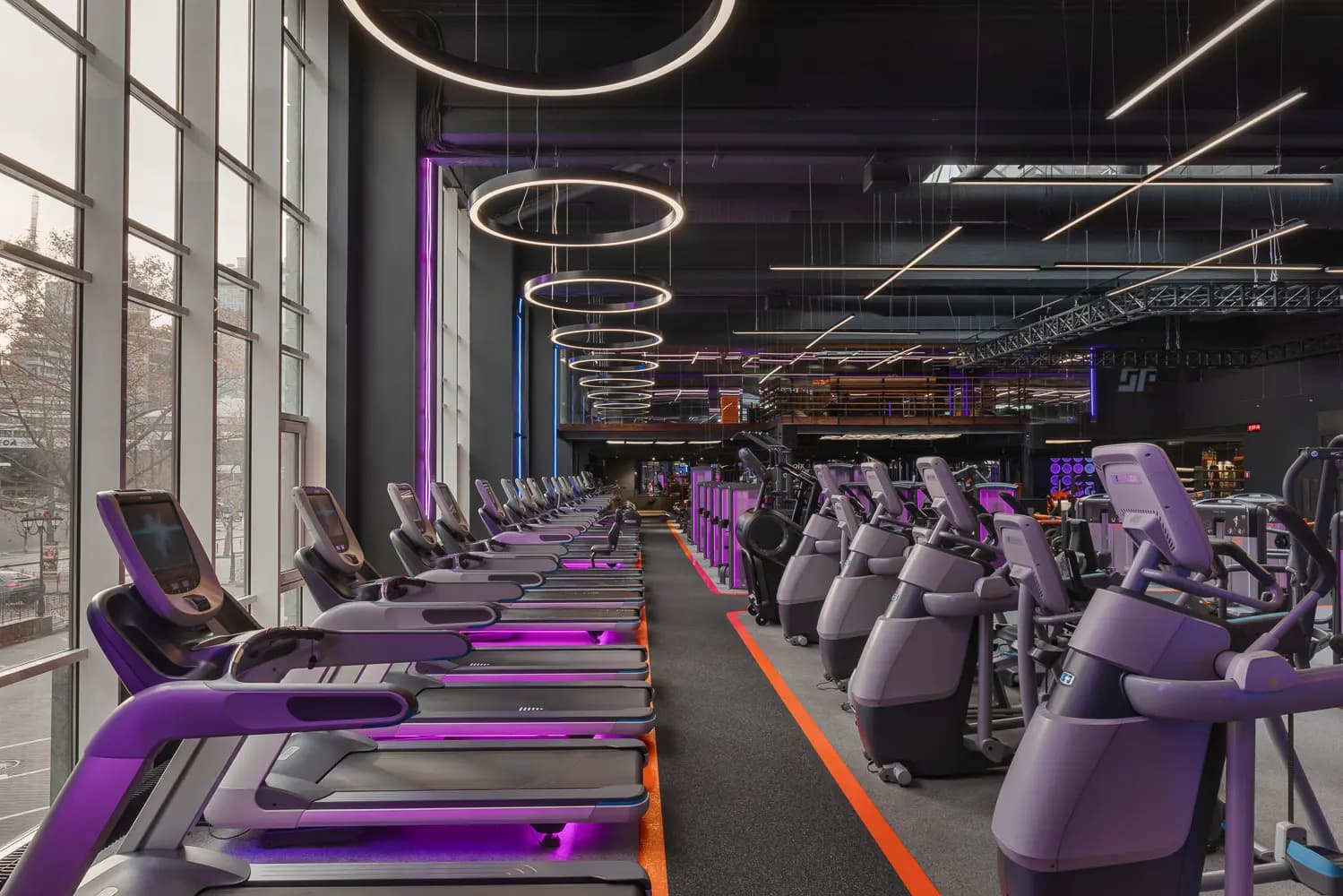 Neon-lit entrance corridor with mirrored walls and red and blue ceiling elements at Synergy Fitness & Spa.