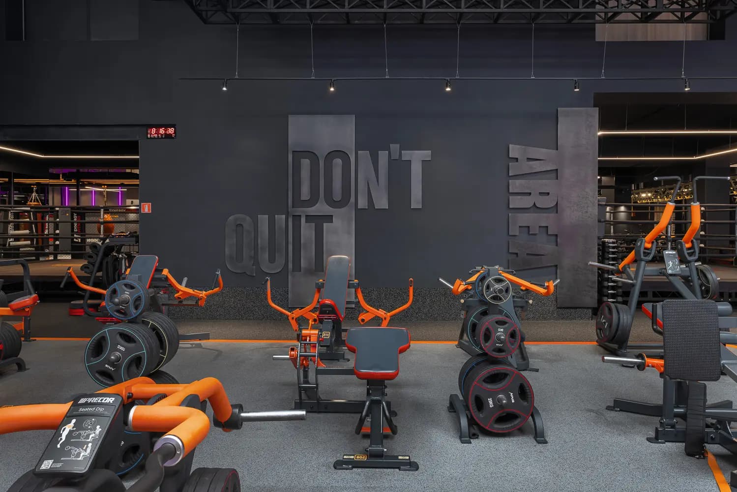 Cycling studio with orange bikes, dark walls and a large motivational graphic.