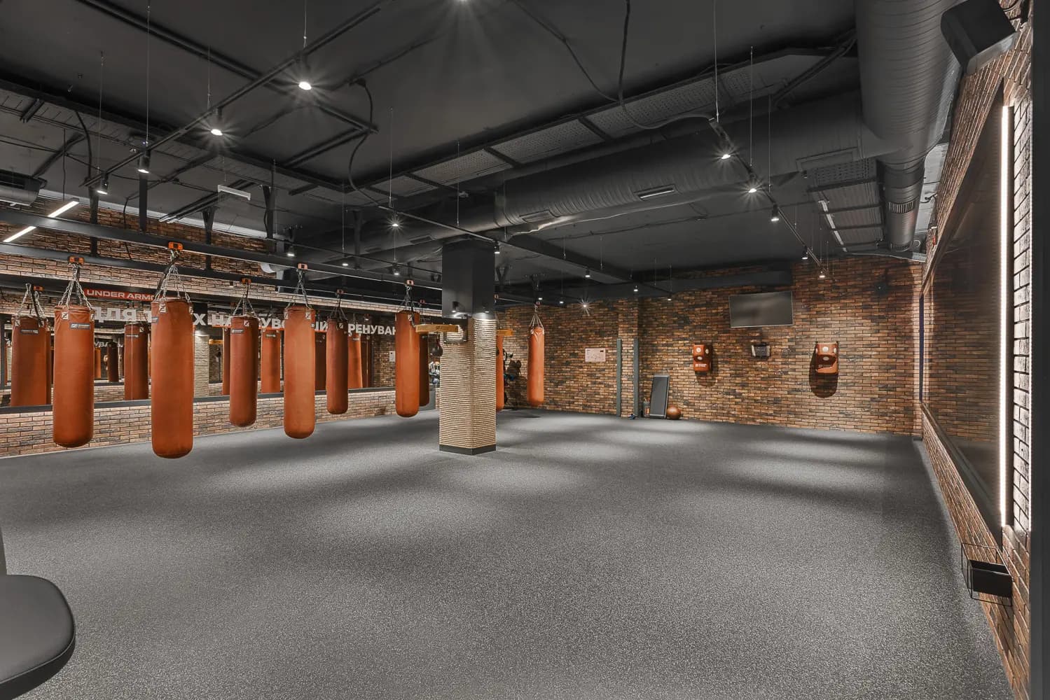 Fight club training hall with suspended punch bags, textured walls and resilient flooring.