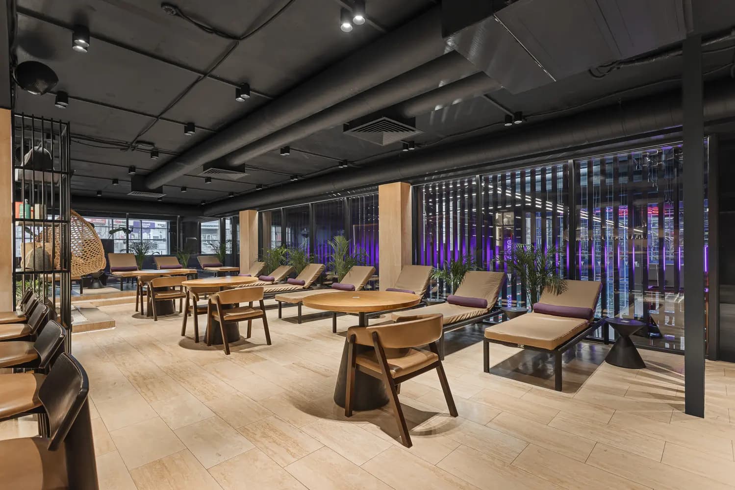 Social lounge with pale tables, upholstered seating, planting and views into the gym.
