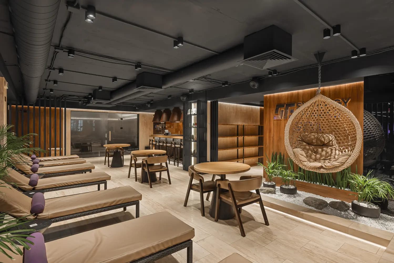 Recovery lounge with timber banquettes, natural stone surfaces and integrated greenery.
