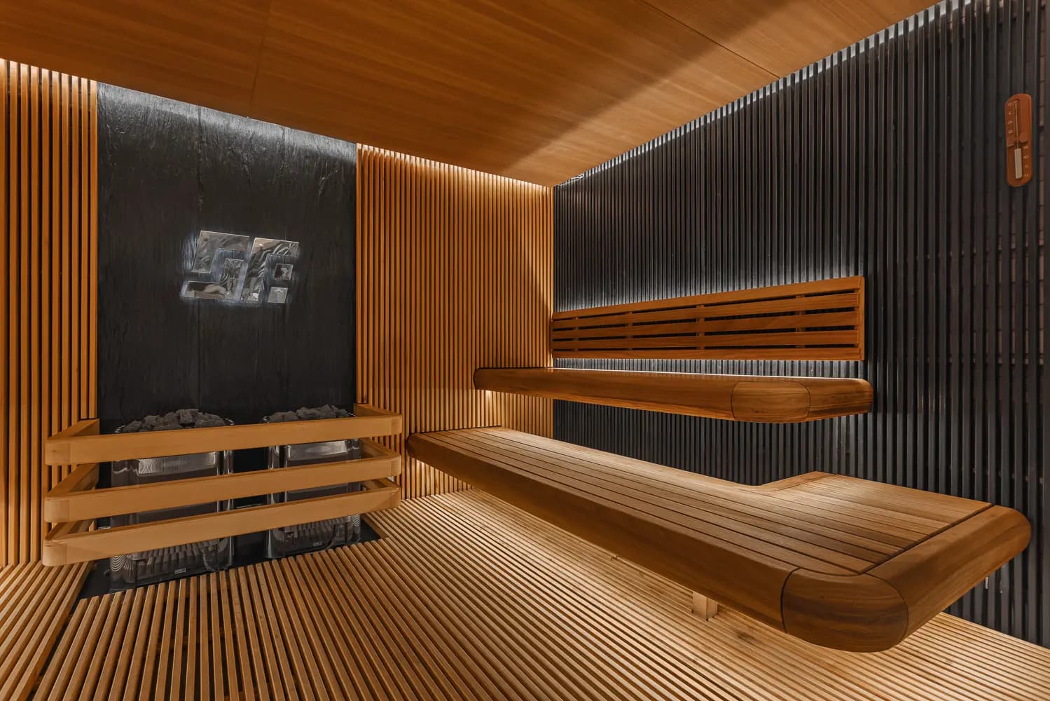 Timber sauna with layered benches, vertical slats and concealed warm lighting.