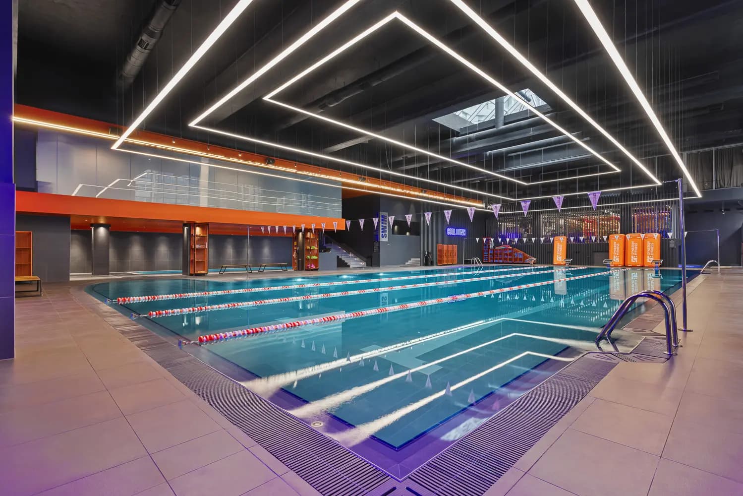 Indoor swimming pool with blue lanes, mirrored ceiling panels and orange perimeter accents.