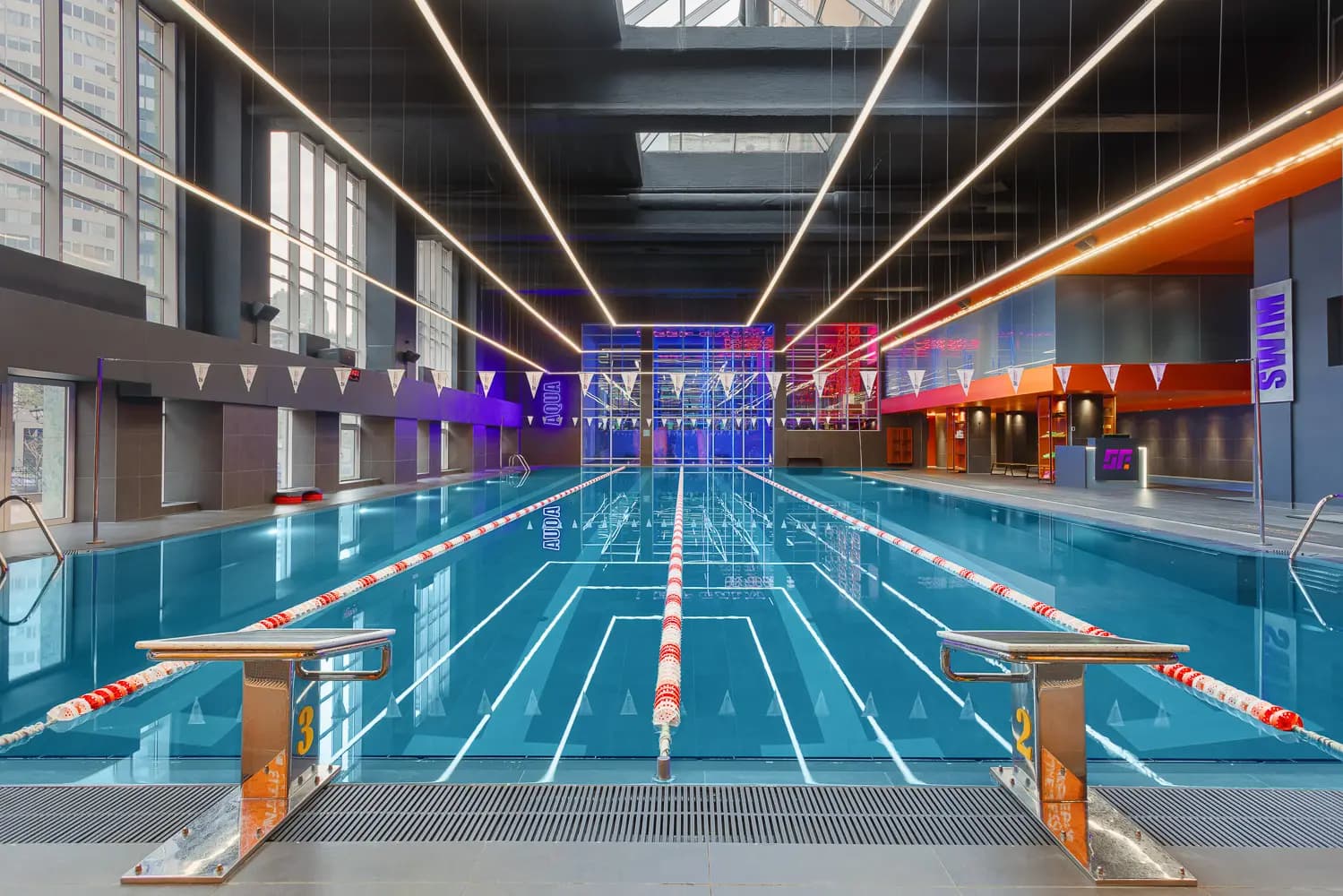 Frontal view along the lap pool beneath geometric linear lighting.