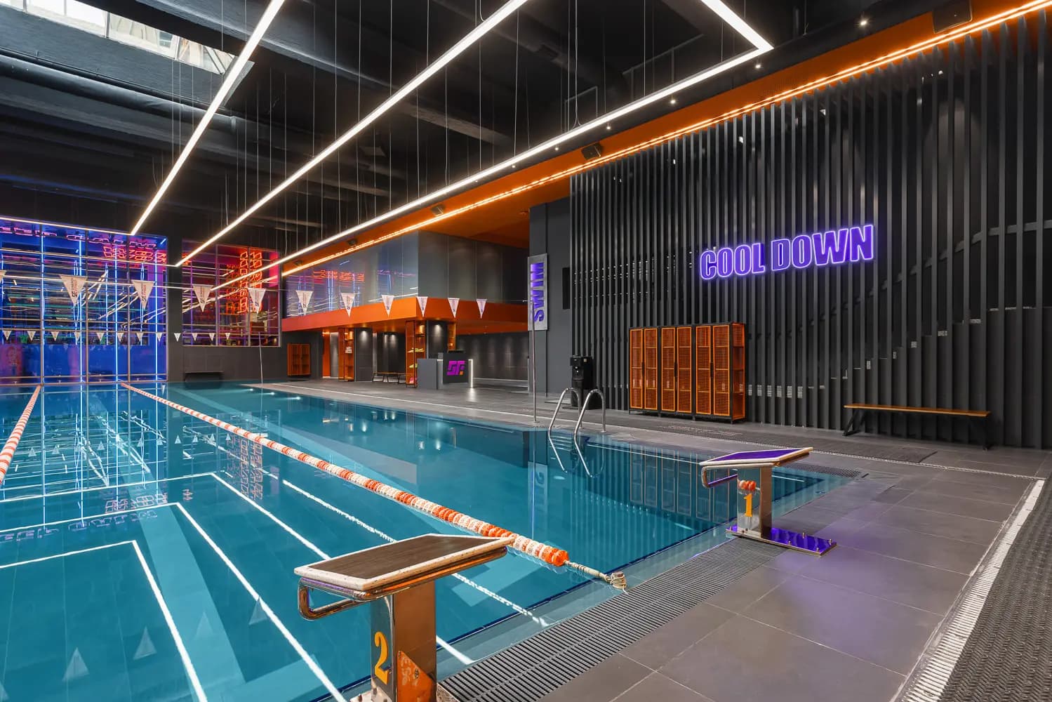 Poolside view with turquoise water, purple signage and orange changing-room elements.