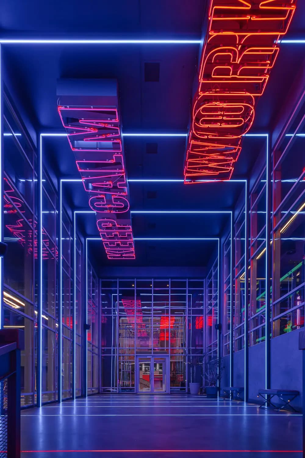 Mirrored entrance corridor with red and blue illuminated ceiling structures.