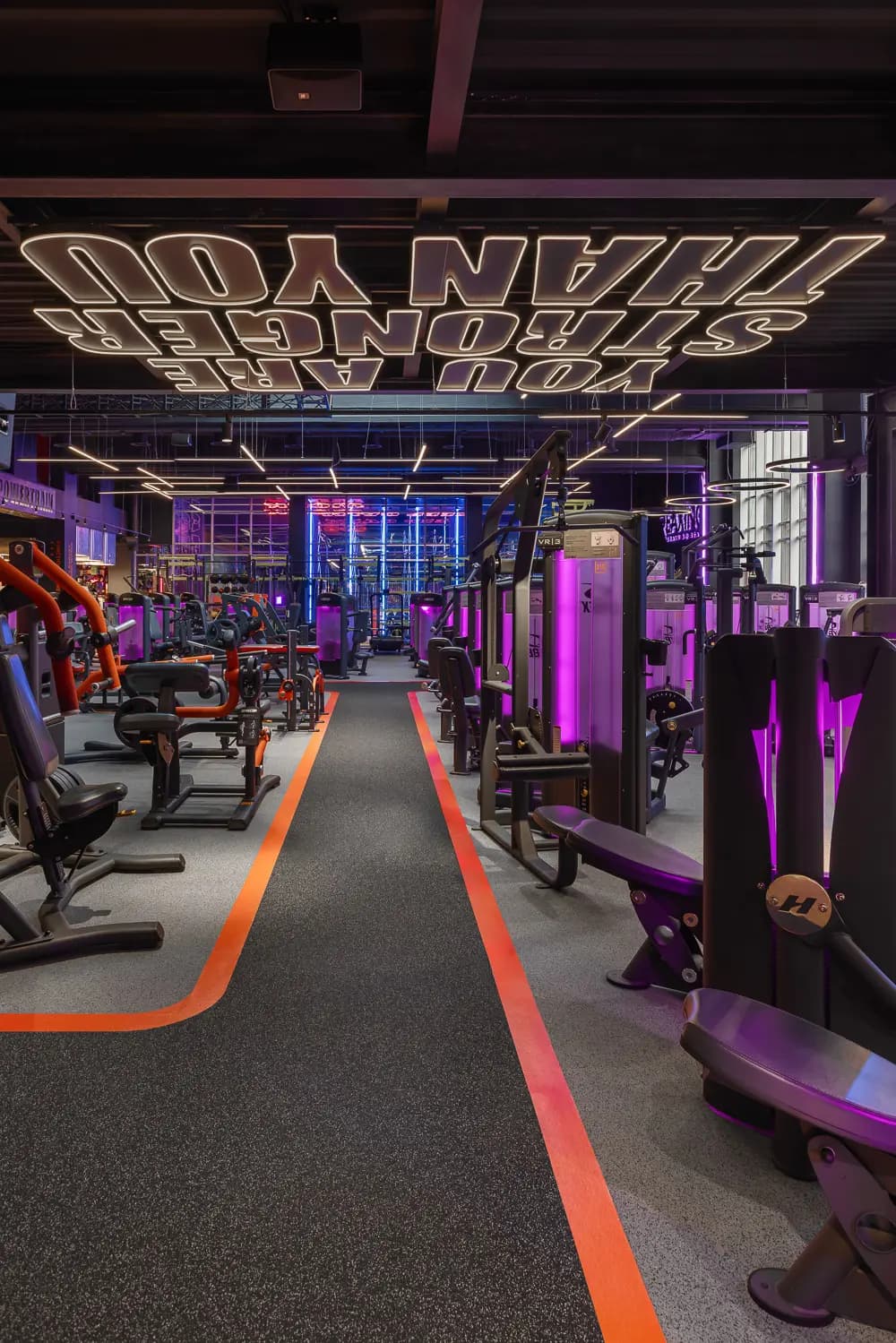 Main training route with strength machines, geometric lighting and orange floor graphics.