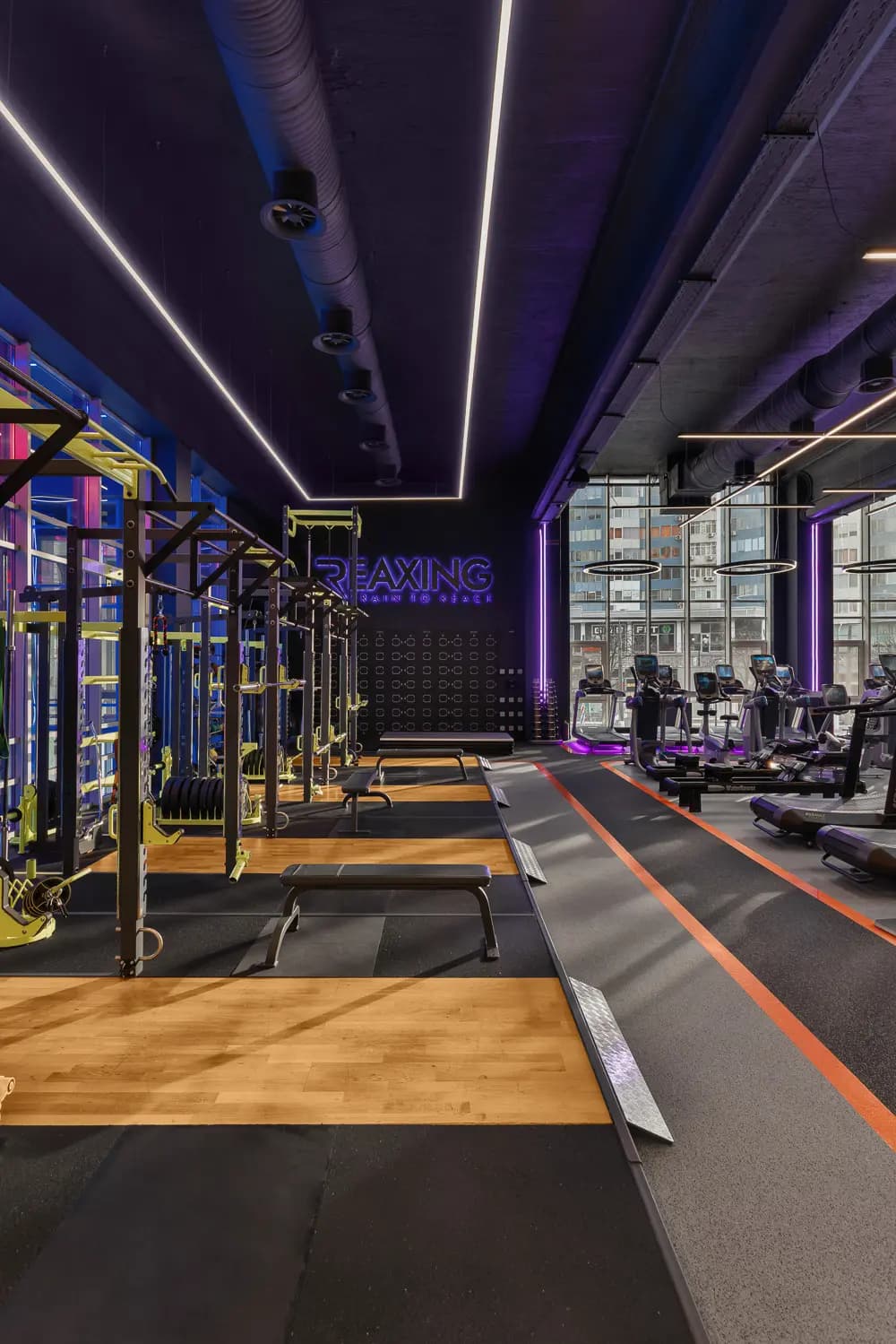 Functional training zone with black equipment, violet lighting and yellow metal structures.