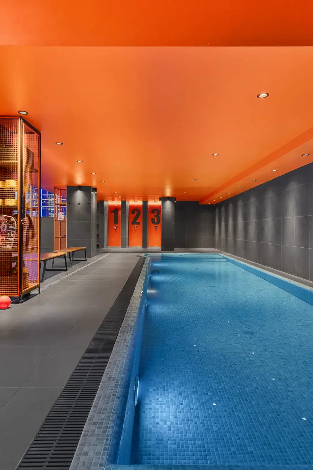 Indoor swimming pool beneath a vivid orange ceiling.