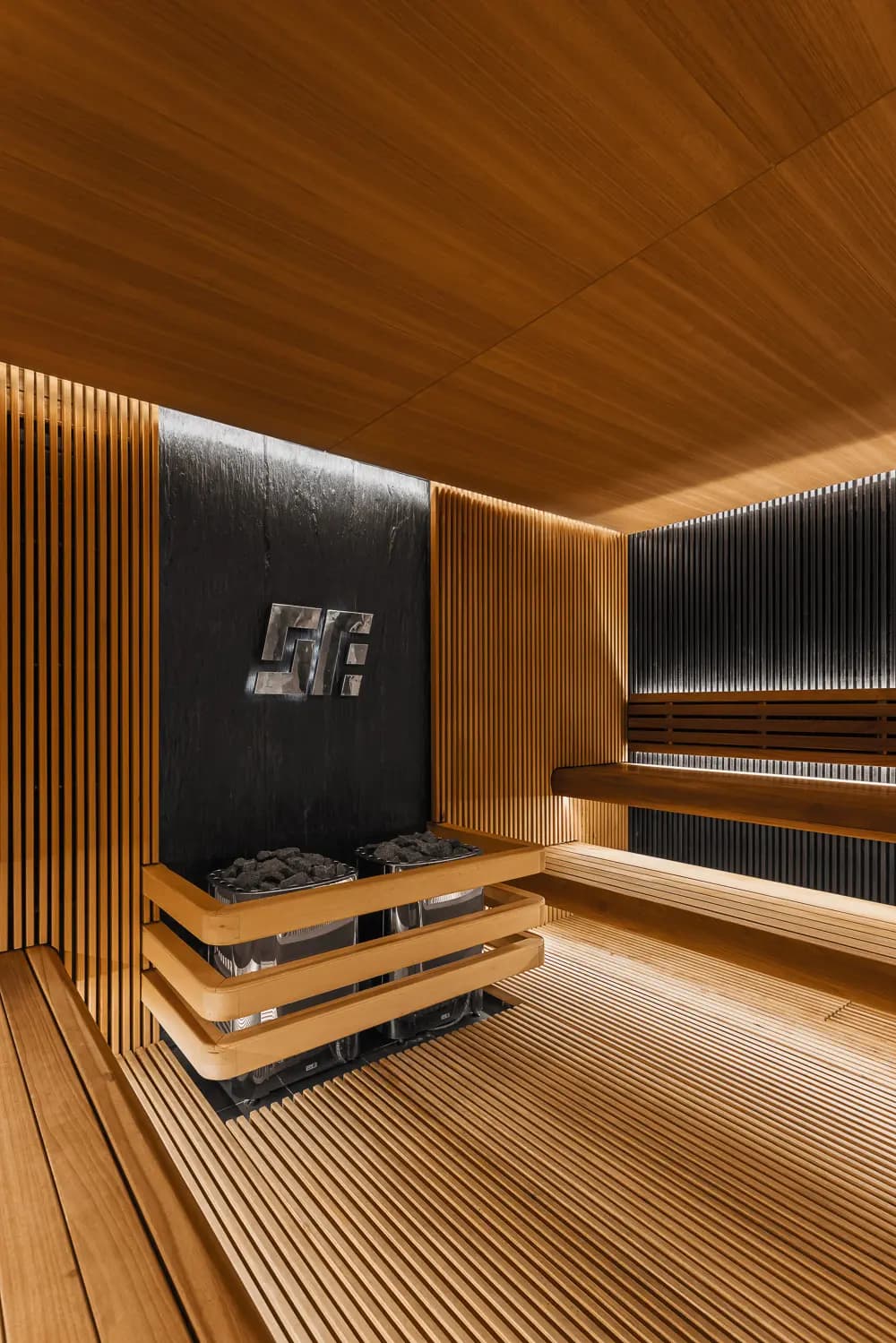 Compact sauna with layered timber benches, slatted walls and indirect lighting.1