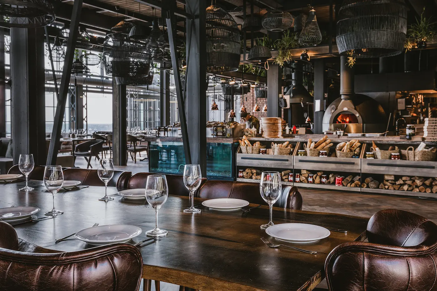 Open-plan interior of YUG Restaurant in Odesa with a turquoise bar, wine display and custom chandeliers.